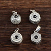 Four silver-tone rotating pendants with black centers displayed on a wooden surface
