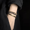 Multi-layer bracelet with black lava rock beads and metal coil on wrist