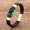Black leather bracelet with a green stone ring and gold-tone metal accents
