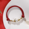 Close up of a woven red string bracelet with a silver horse charm on a wrist