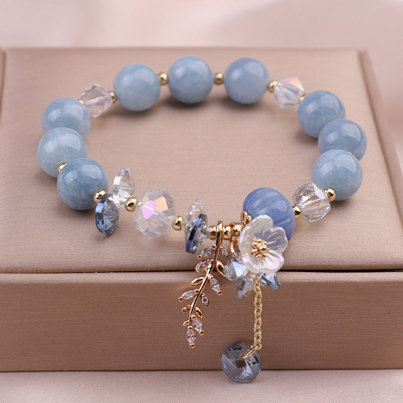 Blue stone beaded bracelet with gold flower charm on a box
