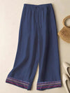 Navy blue wide leg pants with embroidered hem detail laid flat on a neutral surface