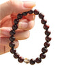 Close up of a dark red wood beaded bracelet with one clear crystal bead