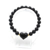 A beaded bracelet made of black obsidian stones with a central heart-shaped charm on a display stand