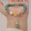 Green jade bead bracelet with pearl and pink quartz accents held in hand