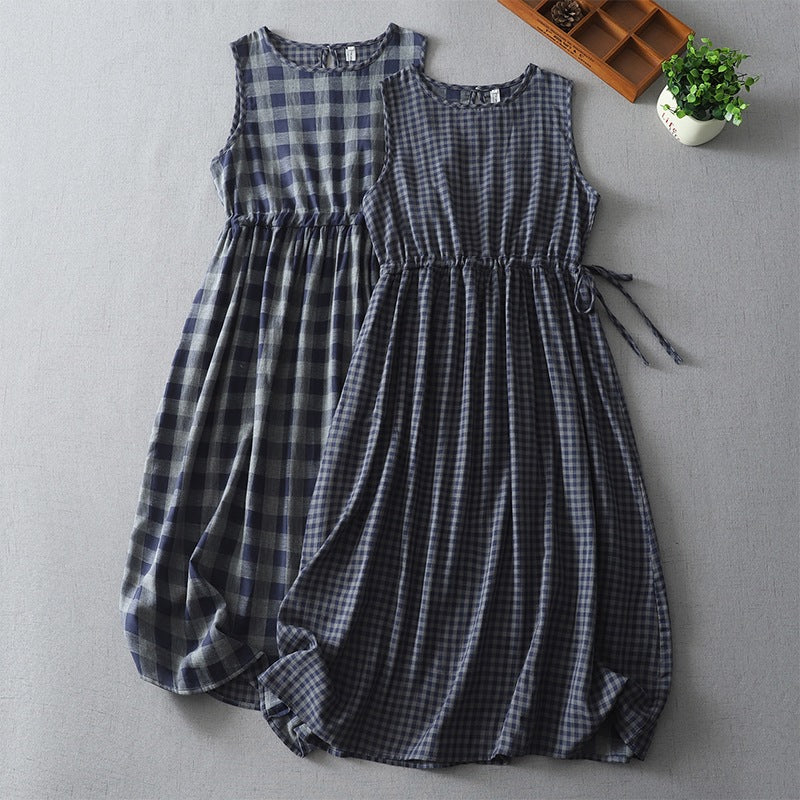 Two blue and white plaid sleeveless dresses lying flat on a grey surface