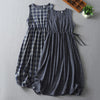 Two blue and white plaid sleeveless dresses lying flat on a grey surface