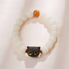 Close up of a white bodhi seed bracelet with a black wooden cat head charm