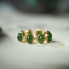 Close up of a silver ring with green stones on a white surface