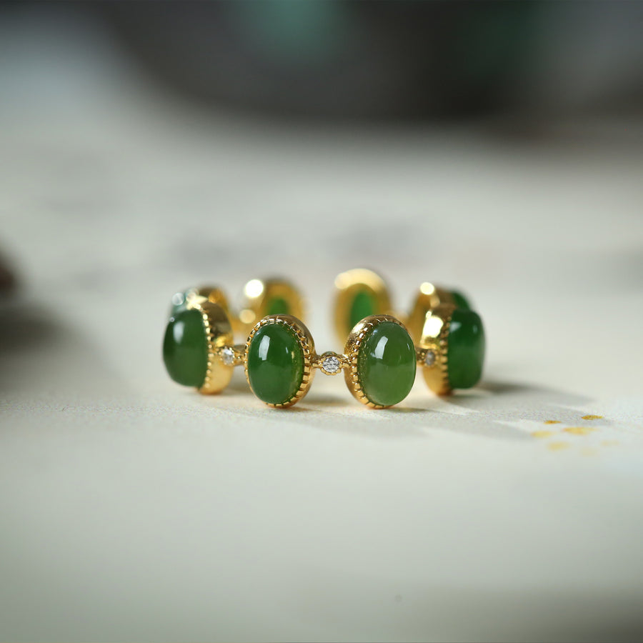 Close up of a silver ring with green stones on a white surface