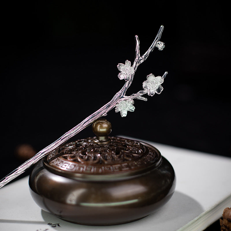 A silver-tone alloy hairpin shaped like a flowering branch worn in dark hair