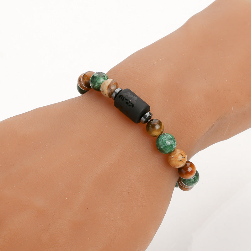 A beaded bracelet with green and brown stones worn on a wrist