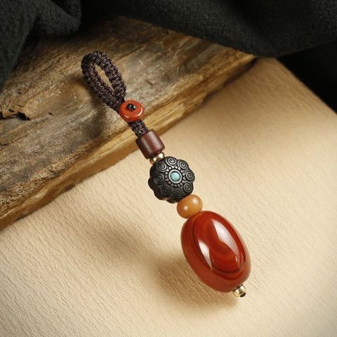 Close up of a wooden bead keychain with a large red agate stone attached to a car key fob.
