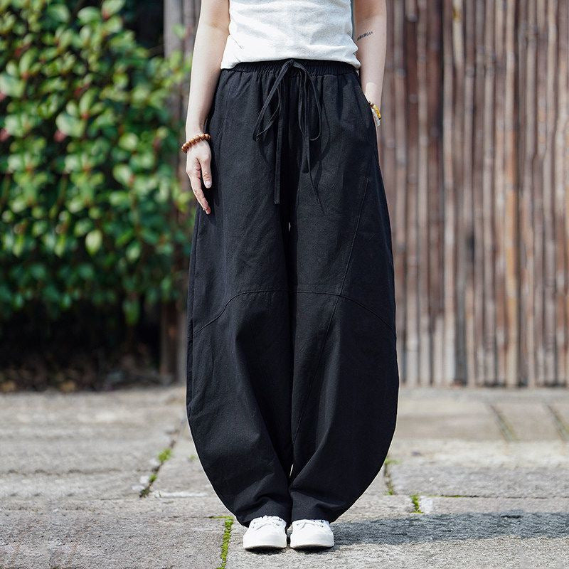 Model wearing black wide leg harem pants with a drawstring waist