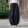 Model wearing black wide leg harem pants with a drawstring waist