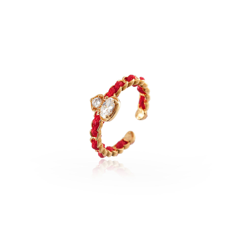 Close up of an adjustable ring with a red woven band and a gold gourd charm set with clear stones