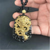 Close-up of a hand holding a black obsidian pendant with a raised gold dragon design