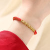 Close-up of a red and gold braided bracelet on a wrist