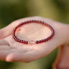 Woman wearing a red beaded bracelet with a pink accent bead