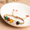A close-up view of a multicolor woven bracelet with five beads