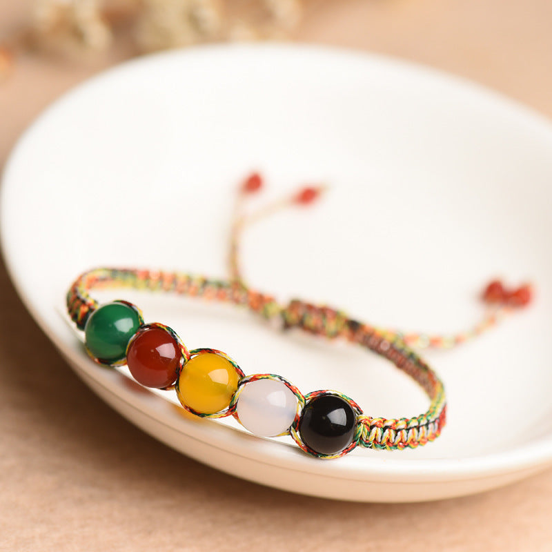 A close-up view of a multicolor woven bracelet with five beads