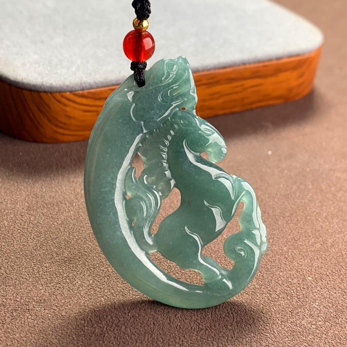 Green jade pendant carved with a horse and dragon design on a black cord