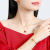 Gold tone necklace and bracelet featuring a red rocking horse charm worn by a woman in red