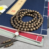 Coiled 108-bead Golden Silk Nanmu wood mala bracelet resting on stacked books