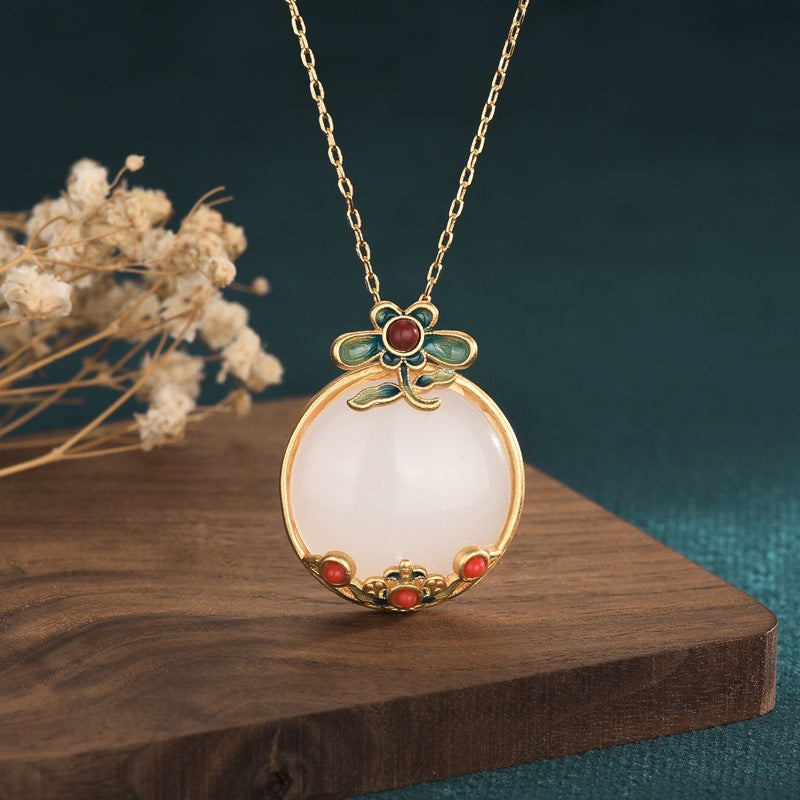 Gold-tone necklace with a round white jade-style pendant featuring blue floral accents
