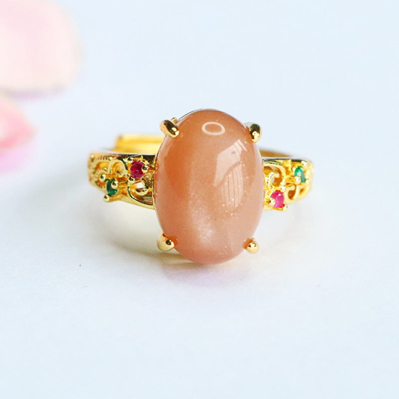 Close up of an orange moonstone ring with gold tone vine details