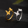 Two butterfly rings in gold and silver tones on a dark textured surface