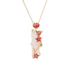 Gold-tone necklace with white bamboo pendant and red lotus flowers on a wooden surface