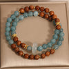 A double-wrap bracelet made of brown Kuka seeds and blue agate beads with a white jade donut charm.