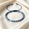 Blue natural stone barrel bead bracelet with silver spacers on a cream background