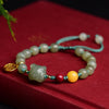 Close up of a light green jade bracelet with a carved tiger charm and red and yellow accent beads