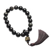 Black obsidian beaded bracelet with tassel resting on a book