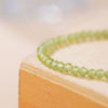 Close up of a green faceted crystal bead bracelet on a wooden block