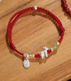 Close up of red beaded bracelet with silver horse charm on wrist