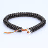 Dark brown bead bracelet with colorful tassel and silver charm on white background