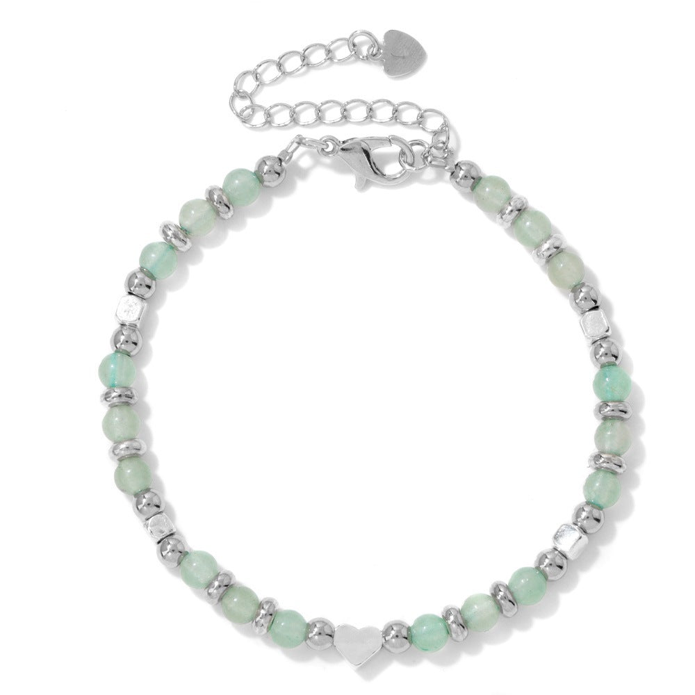 Silver-tone bracelet with light green stone beads and a heart charm on a white background