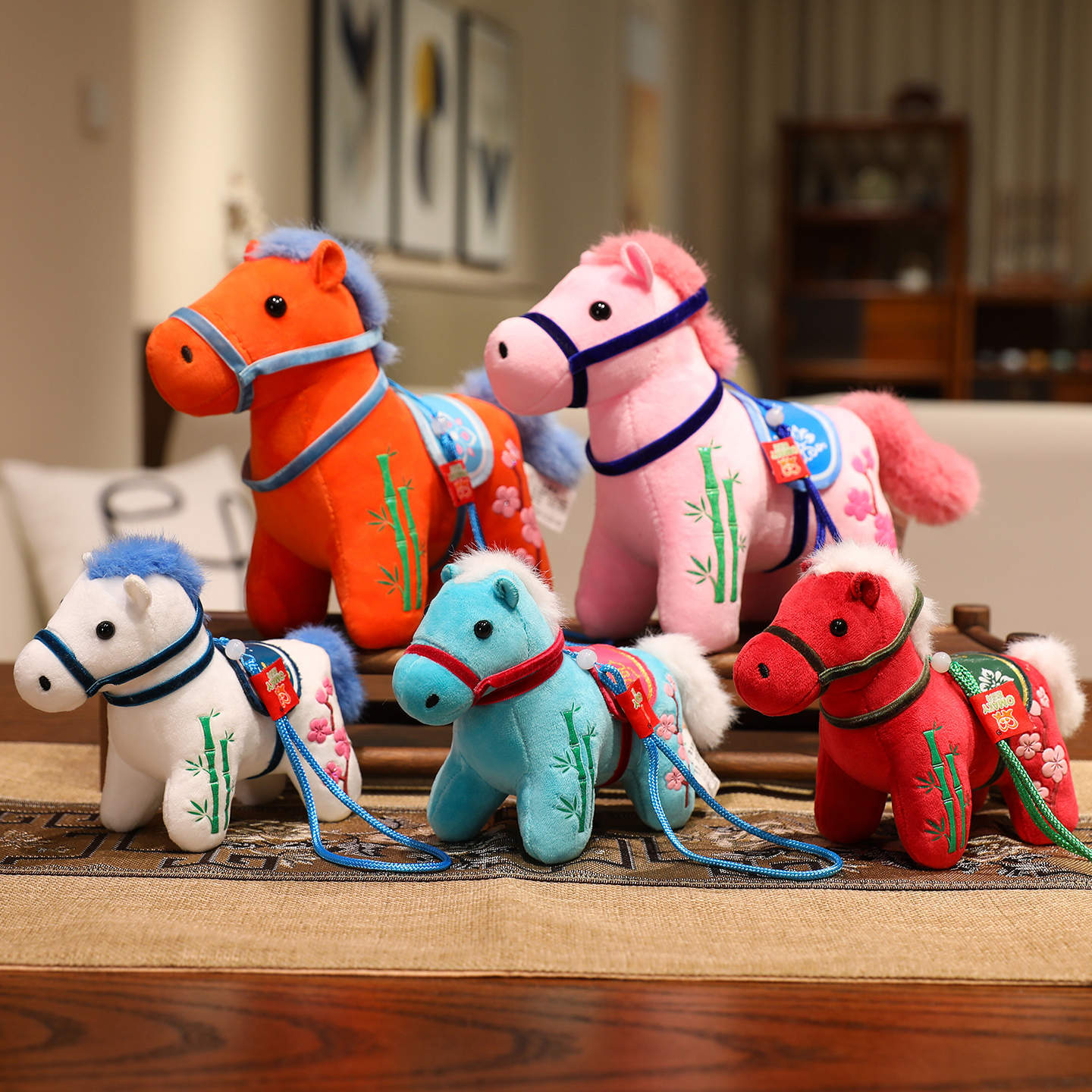 Group of colorful embroidered plush horse dolls sitting on a wooden table