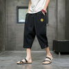 Man wearing navy blue cropped pants with a drawstring waist and side pockets.