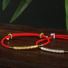 Close up of silver and gold plated bracelets with mantra engraving on red cord