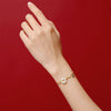 Woman wearing a red string bracelet with a white jade peace buckle charm against a red background