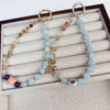 Two beaded crystal phone charms with large metal rings resting on a jewelry display tray