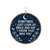 Round blue metal wall sign with moon and stars hanging on a wooden post outdoors