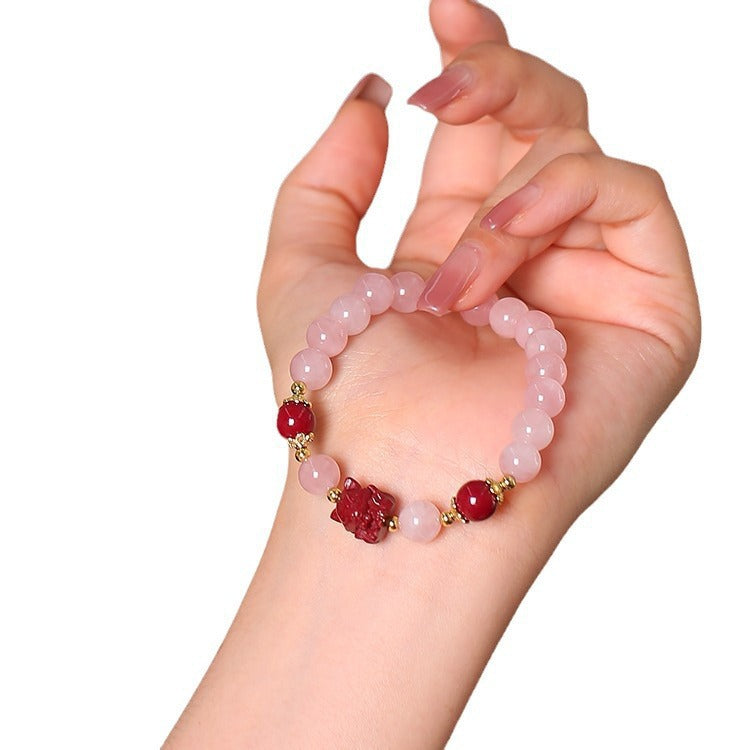Close up of a hand wearing a pink crystal beaded bracelet with a red fox charm