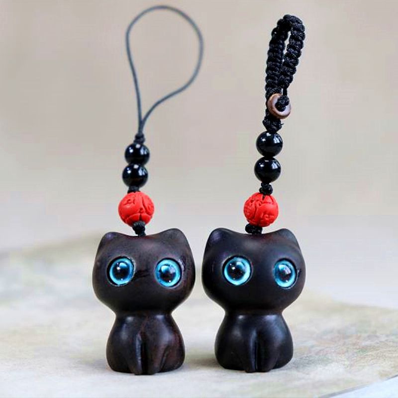 Two wooden cat charms, one dark ebony and one reddish brown, sitting side by side.