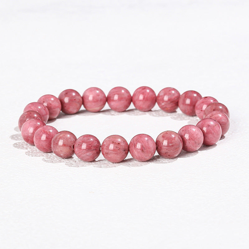 Close up of a pink rhodochrosite beaded bracelet on a white surface