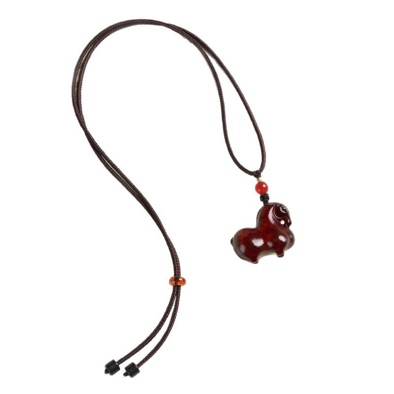 Red sandalwood horse pendant hanging on a brown woven cord against a white background
